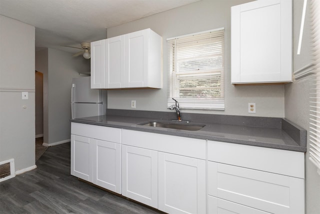 4115 11th St, Des Moines, IA 50313 - kitchen with dark countertops, a ceiling fan, and white cabinetry