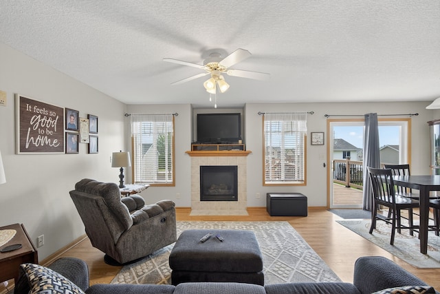 2618 13th St SW, Altoona, IA 50009 - living room featuring wood finished floors, a fireplace, a ceiling fan, and a textured ceiling