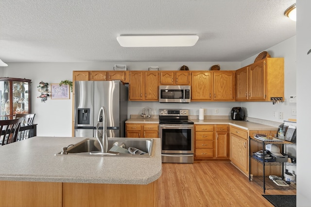 2618 13th St SW, Altoona, IA 50009 - kitchen featuring appliances with stainless steel finishes, light countertops, light wood finished floors, a textured ceiling, and brown cabinets