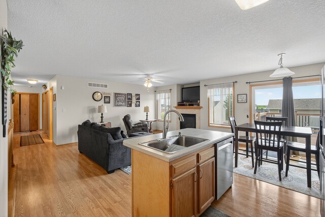 2618 13th St SW, Altoona, IA 50009 - kitchen featuring stainless steel dishwasher, a textured ceiling, a fireplace, light wood-style flooring, and a ceiling fan