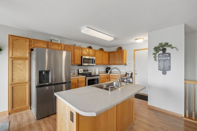 2618 13th St SW, Altoona, IA 50009 - kitchen featuring stainless steel appliances, light wood-type flooring, light countertops, a center island with sink, and a textured ceiling