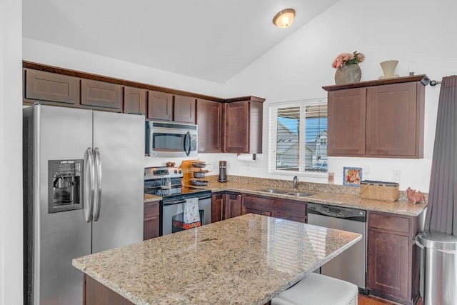 704 36th St SW, Bondurant, IA 50035 - kitchen featuring appliances with stainless steel finishes, vaulted ceiling, a kitchen island, and light stone countertops