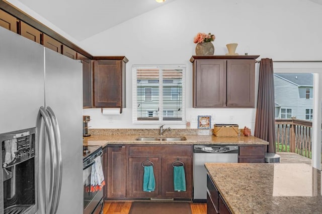 704 36th St SW, Bondurant, IA 50035 - kitchen featuring appliances with stainless steel finishes, lofted ceiling, light stone counters, light wood-type flooring, and dark brown cabinets
