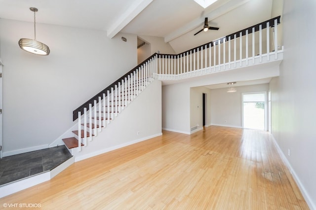 2729 Meadow Point Ct, West Des Moines, IA 50265 - unfurnished living room featuring beam ceiling, a ceiling fan, wood finished floors, high vaulted ceiling, and stairs