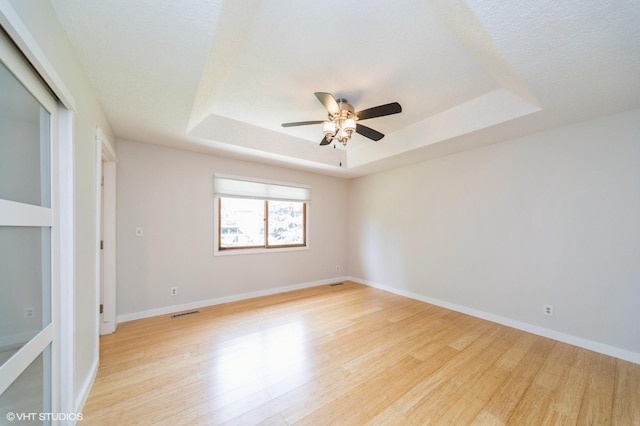 2729 Meadow Point Ct, West Des Moines, IA 50265 - empty room with a raised ceiling, light wood-style flooring, and a ceiling fan