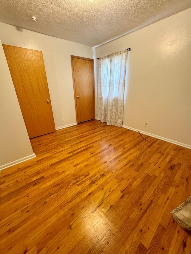 2611 E 38th St, Des Moines, IA 50317 - unfurnished bedroom with wood finished floors and a textured ceiling