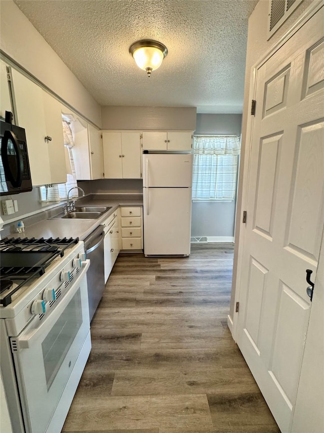 2611 E 38th St, Des Moines, IA 50317 - kitchen with white appliances, a textured ceiling, wood finished floors, and white cabinets