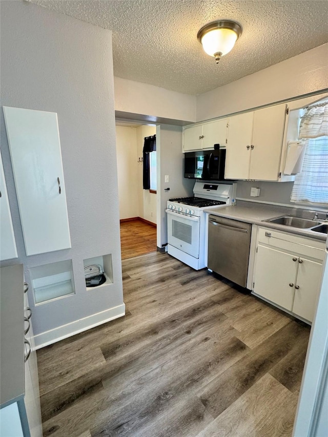 2611 E 38th St, Des Moines, IA 50317 - kitchen featuring dishwasher, white range with gas stovetop, black microwave, white cabinets, and a textured ceiling