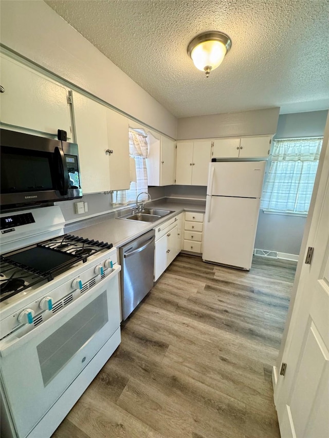 2611 E 38th St, Des Moines, IA 50317 - kitchen with stainless steel appliances, a textured ceiling, wood finished floors, and white cabinetry