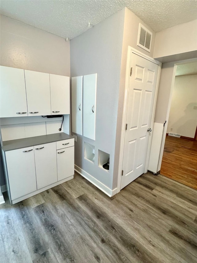 2611 E 38th St, Des Moines, IA 50317 - kitchen featuring white cabinetry, wood finished floors, a textured ceiling, and dark countertops
