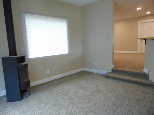 2340 Des Moines St, Des Moines, IA 50317 - unfurnished living room with a wood stove, carpet flooring, and recessed lighting