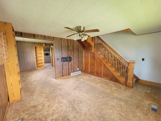 108 W Logan St, Casey, IA 50048 - unfurnished living room featuring carpet, wooden walls, a ceiling fan, and stairway