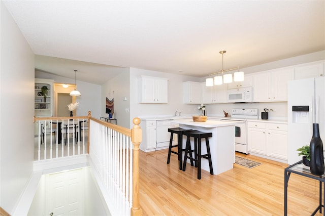 7316 SE 23rd St Unit 5, Des Moines, IA 50320 - kitchen with white appliances, a kitchen island, white cabinetry, light wood finished floors, and light countertops