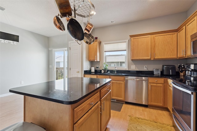 263 SE Booth Ave, Waukee, IA 50266 - kitchen with appliances with stainless steel finishes, light wood-type flooring, dark countertops, and a kitchen island