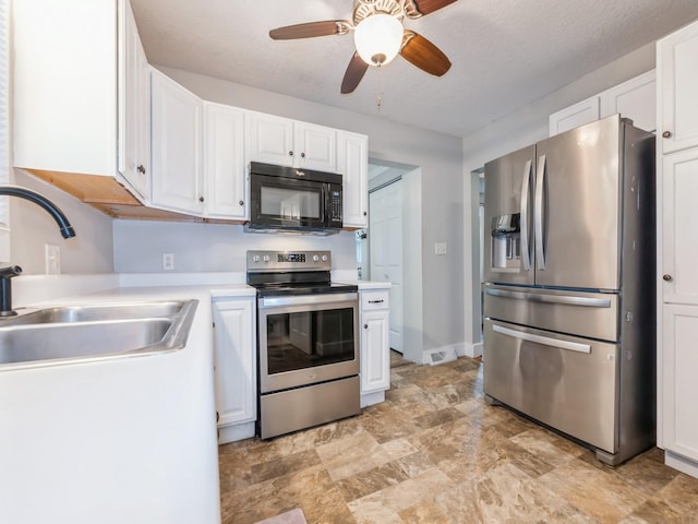 715 N Fremont St, Stuart, IA 50250 - kitchen with appliances with stainless steel finishes, a ceiling fan, white cabinetry, light countertops, and stone finish floors