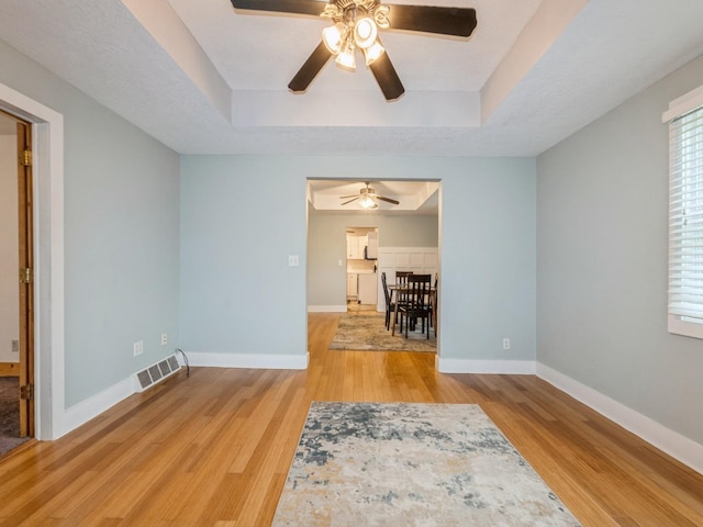 715 N Fremont St, Stuart, IA 50250 - spare room featuring a ceiling fan, a tray ceiling, and wood finished floors