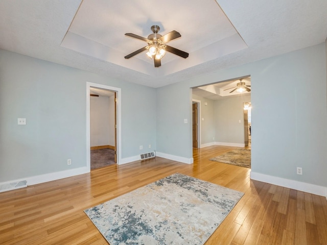 715 N Fremont St, Stuart, IA 50250 - spare room with a tray ceiling, ceiling fan, and light wood-style floors