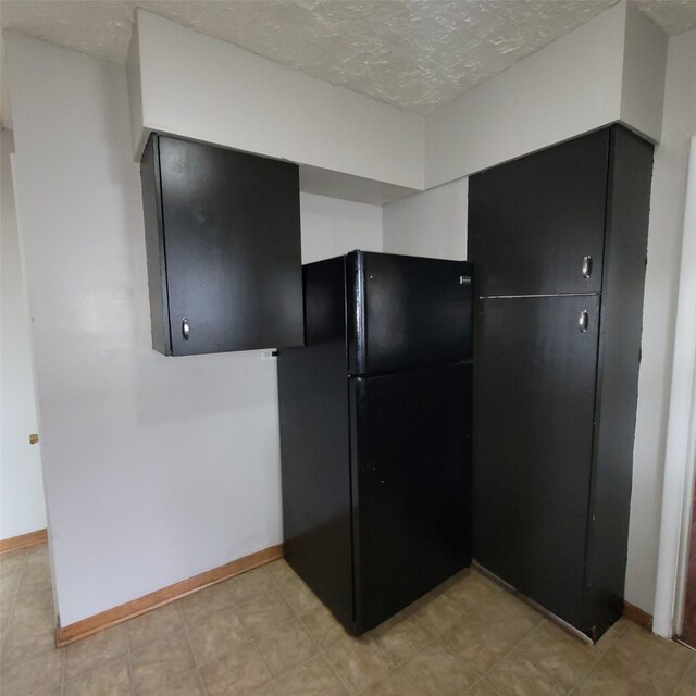 3224 SW 13th Pl, Des Moines, IA 50315 - kitchen with freestanding refrigerator, a textured ceiling, and dark cabinets