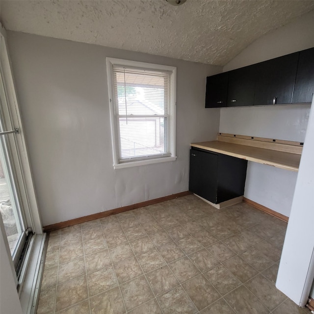 3224 SW 13th Pl, Des Moines, IA 50315 - kitchen featuring dark cabinets, a textured ceiling, lofted ceiling, built in study area, and light countertops