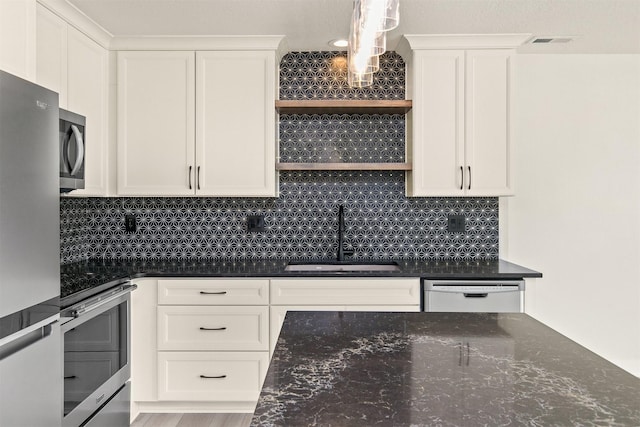 8302 Westown Pkwy Unit 1102, West Des Moines, IA 50266 - kitchen featuring appliances with stainless steel finishes, white cabinets, dark stone countertops, and decorative backsplash