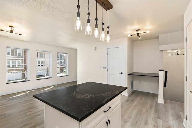 8302 Westown Pkwy Unit 1102, West Des Moines, IA 50266 - kitchen featuring light wood-type flooring, white cabinets, decorative light fixtures, open floor plan, and a textured ceiling