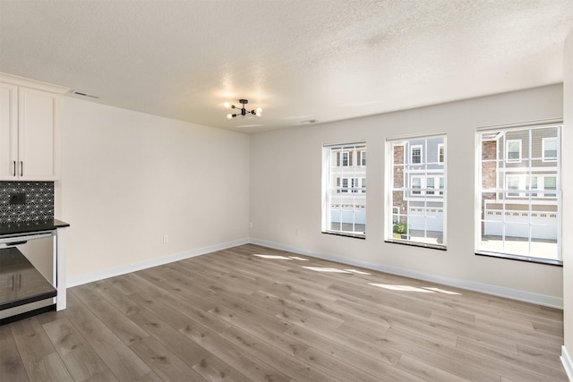 8302 Westown Pkwy Unit 1102, West Des Moines, IA 50266 - unfurnished living room with light wood-style floors, a textured ceiling, and a chandelier