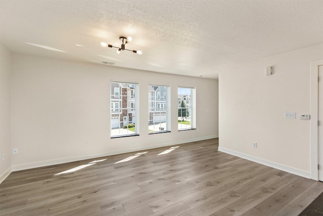 8302 Westown Pkwy Unit 1102, West Des Moines, IA 50266 - unfurnished room with wood finished floors, a chandelier, and a textured ceiling
