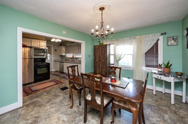 5910 Tonka Ave, Des Moines, IA 50312 - dining space with a chandelier, stone finish flooring, and a textured ceiling