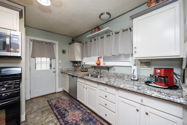 5910 Tonka Ave, Des Moines, IA 50312 - kitchen featuring appliances with stainless steel finishes, white cabinetry, a textured ceiling, and light stone countertops
