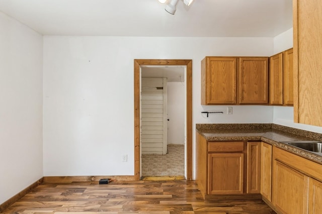 1805 S D Ave, Lovilia, IA 50150 - kitchen with wood finished floors, dark countertops, and brown cabinets