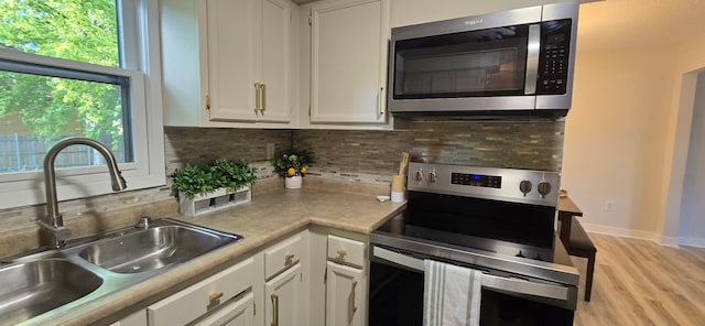 2209 4th St SW, Altoona, IA 50009 - kitchen featuring appliances with stainless steel finishes, white cabinets, tasteful backsplash, and light wood-style floors