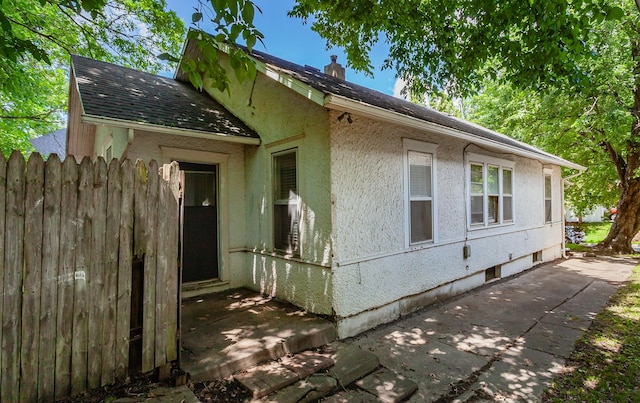 802 Fulton Dr, Des Moines, IA 50315 - view of home's exterior featuring stucco siding, roof with shingles, and a patio