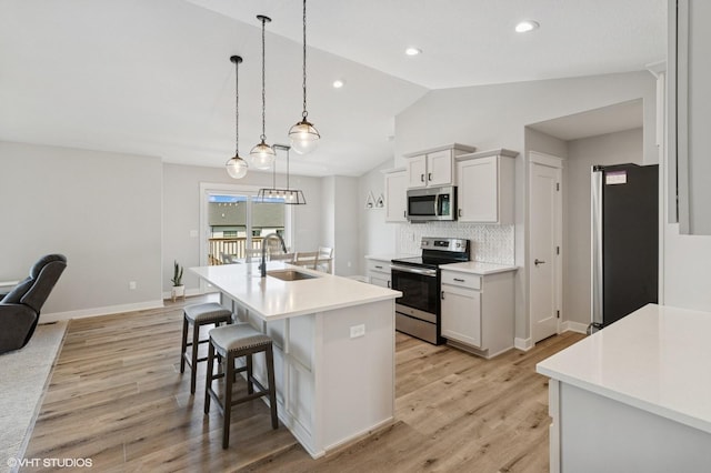 2670 Long Ave, Van Meter, IA 50261 - kitchen featuring appliances with stainless steel finishes, vaulted ceiling, light countertops, decorative backsplash, and a kitchen bar