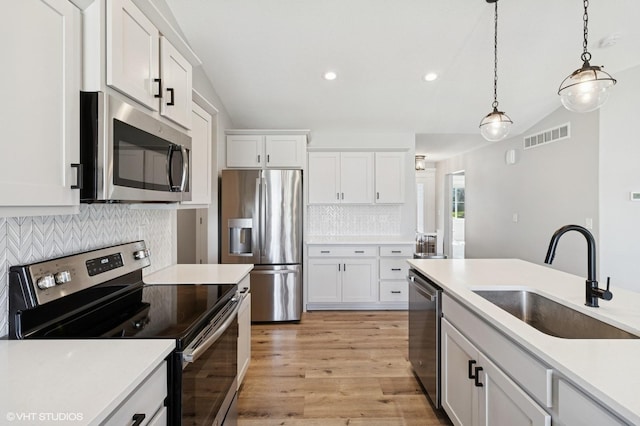 2670 Long Ave, Van Meter, IA 50261 - kitchen with appliances with stainless steel finishes, lofted ceiling, backsplash, white cabinetry, and light countertops