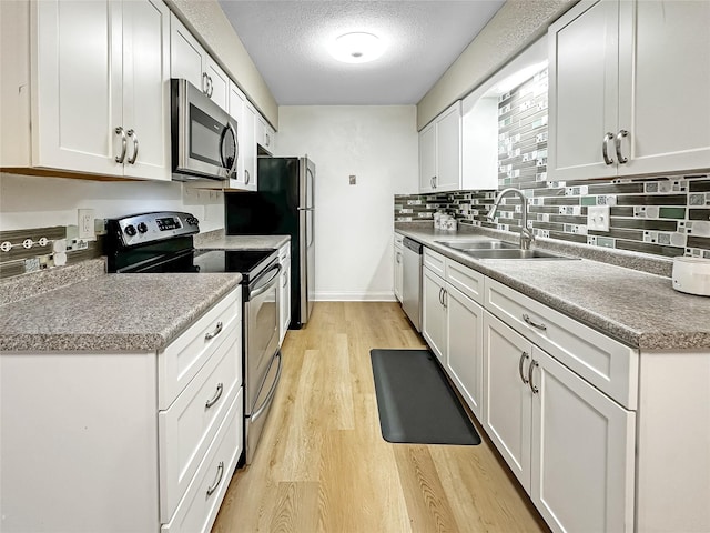 9513 University Ave Unit 12, Clive, IA 50325 - kitchen featuring appliances with stainless steel finishes, light wood-type flooring, white cabinetry, tasteful backsplash, and a textured ceiling