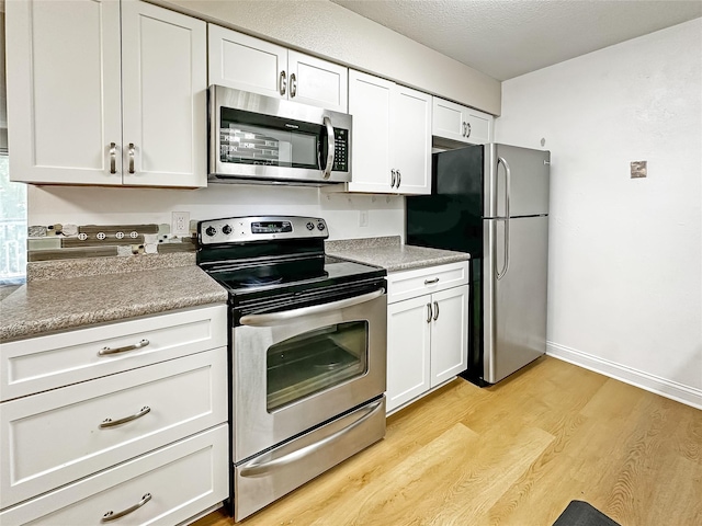 9513 University Ave Unit 12, Clive, IA 50325 - kitchen featuring appliances with stainless steel finishes, white cabinets, light wood-style floors, and light countertops