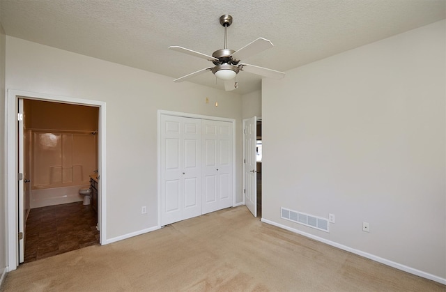8601 Westown Pkwy Unit 5114, West Des Moines, IA 50266 - unfurnished bedroom featuring light colored carpet, a closet, a textured ceiling, connected bathroom, and ceiling fan