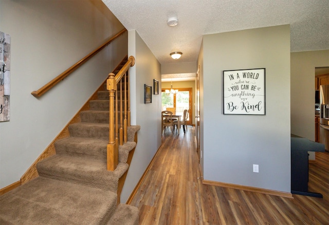 5030 Oakcreek Dr, Norwalk, IA 50211 - staircase featuring wood finished floors, a chandelier, and a textured ceiling