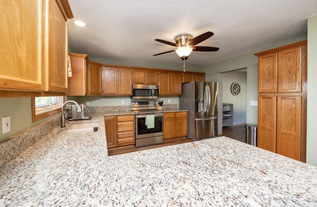 5030 Oakcreek Dr, Norwalk, IA 50211 - kitchen featuring stainless steel appliances, a ceiling fan, light stone countertops, brown cabinets, and recessed lighting
