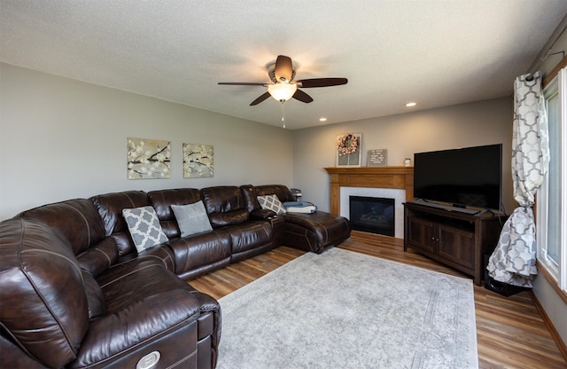 5030 Oakcreek Dr, Norwalk, IA 50211 - living room featuring a ceiling fan, wood finished floors, a glass covered fireplace, and recessed lighting