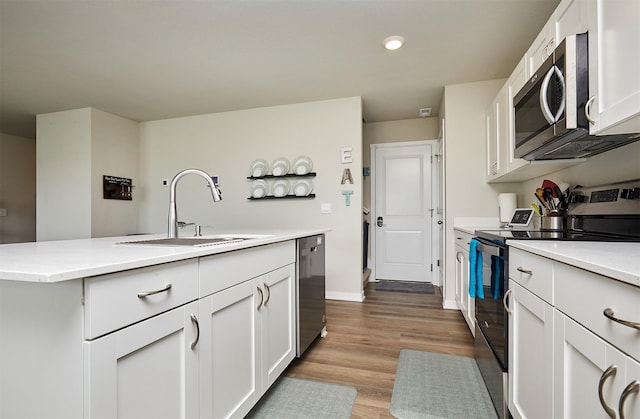 4727 170th Pl, Urbandale, IA 50323 - kitchen with appliances with stainless steel finishes, white cabinets, light countertops, wood finished floors, and a center island with sink