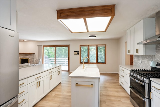 1711 Plaza Cir, Windsor Heights, IA 50324 - kitchen featuring stainless steel appliances, wall chimney range hood, decorative backsplash, a center island with sink, and light countertops