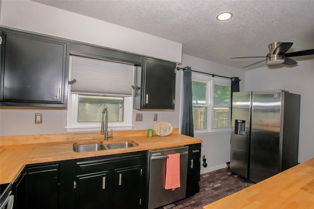 500 Scandia Ave, Des Moines, IA 50315 - kitchen with appliances with stainless steel finishes, butcher block countertops, brick floors, dark cabinetry, and a textured ceiling