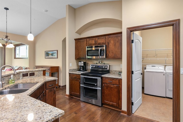 6054 Bradford Ln, Johnston, IA 50131 - kitchen with appliances with stainless steel finishes, washer and dryer, vaulted ceiling, dark wood-style floors, and arched walkways