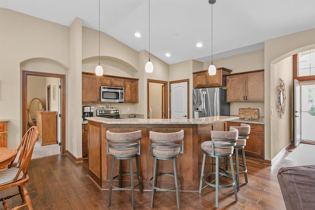 6054 Bradford Ln, Johnston, IA 50131 - kitchen with appliances with stainless steel finishes, dark wood finished floors, brown cabinets, a kitchen bar, and recessed lighting