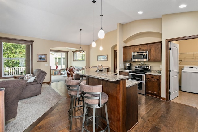 6054 Bradford Ln, Johnston, IA 50131 - kitchen featuring appliances with stainless steel finishes, washer / dryer, arched walkways, open floor plan, and vaulted ceiling