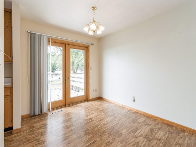 1122 E Ave E, Albia, IA 52531 - unfurnished room featuring french doors, light wood-style flooring, and a chandelier