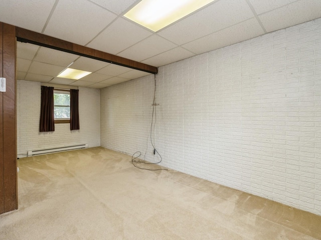 1122 E Ave E, Albia, IA 52531 - below grade area with a paneled ceiling, a baseboard heating unit, carpet, and brick wall