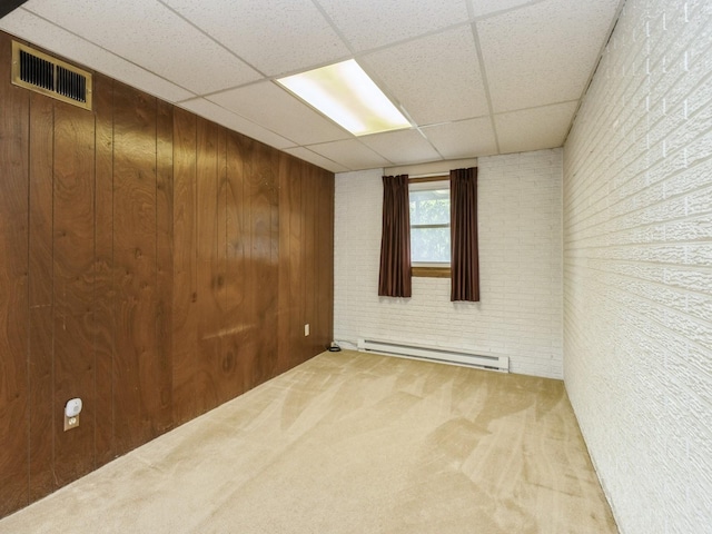 1122 E Ave E, Albia, IA 52531 - carpeted empty room with baseboard heating, a drop ceiling, and wooden walls