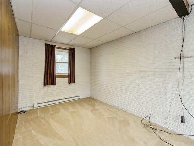 1122 E Ave E, Albia, IA 52531 - spare room with a baseboard radiator, a drop ceiling, brick wall, and carpet floors